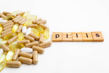 Farklı hapların beyaz arka planında tahta küplere kazınmış yazıtlar.