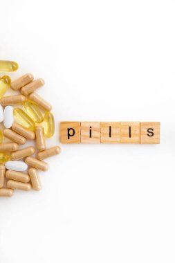 Farklı hapların beyaz arka planında tahta küplere kazınmış yazıtlar.