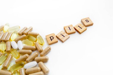 Farklı hapların beyaz arka planında tahta küplere kazınmış yazıtlar.