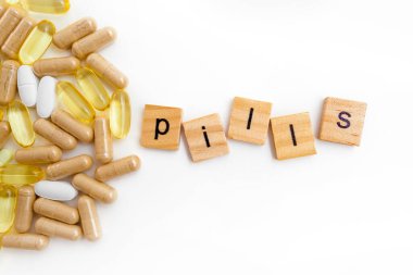 Farklı hapların beyaz arka planında tahta küplere kazınmış yazıtlar.