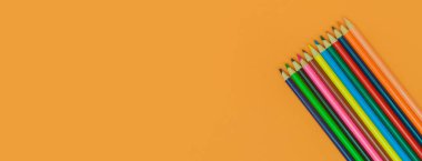 Sarı panorama arka planında renkli kalemler