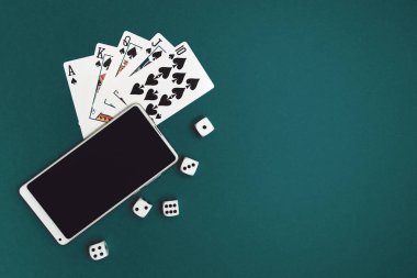 Yeşil mavi kumaş üzerinde poker zarları ve telefon oyunu