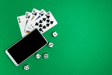 Yeşil mavi kumaş üzerinde poker zarları ve telefon oyunu
