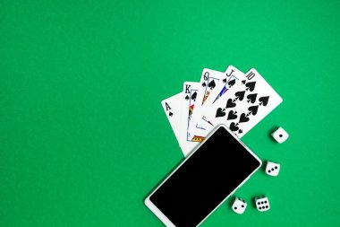 Yeşil mavi kumaş üzerinde poker zarları ve telefon oyunu