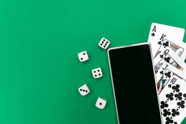 Yeşil mavi kumaş üzerinde poker zarları ve telefon oyunu