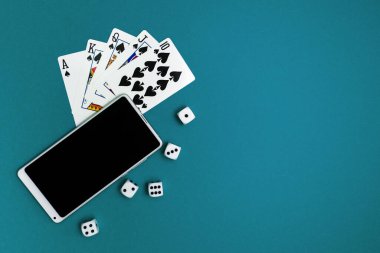 Yeşil mavi kumaş üzerinde poker zarları ve telefon oyunu