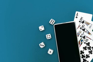 Yeşil mavi kumaş üzerinde poker zarları ve telefon oyunu