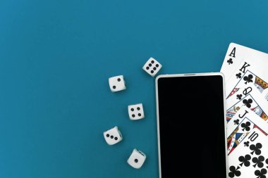 Yeşil mavi kumaş üzerinde poker zarları ve telefon oyunu