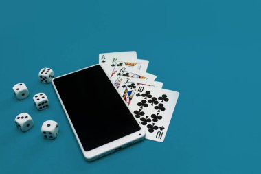 Yeşil mavi kumaş üzerinde poker zarları ve telefon oyunu