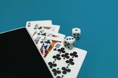 Yeşil mavi kumaş üzerinde poker zarları ve telefon oyunu