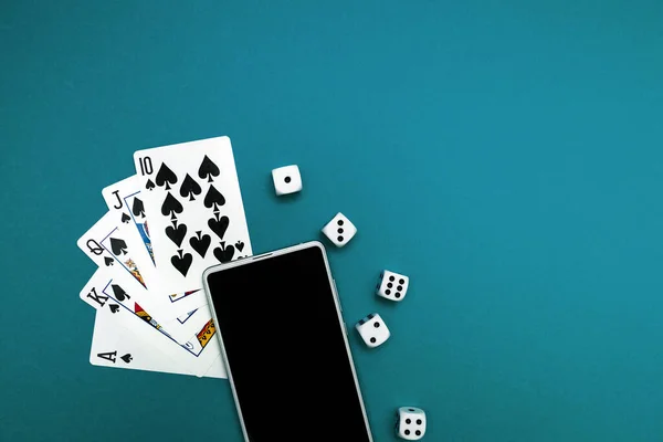 Yeşil mavi kumaş üzerinde poker zarları ve telefon oyunu