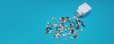 Panorama mavi arka planda kavanozdan düşen çok renkli haplar.