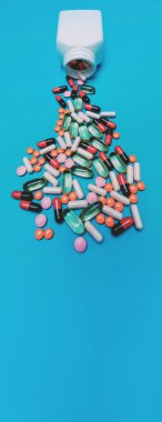 Panorama mavi arka planda kavanozdan düşen çok renkli haplar.