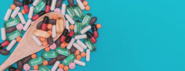 mavi panorama arka planında tahta kaşıkta çok renkli haplar.