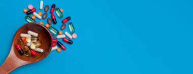 mavi panorama arka planında tahta kaşıkta çok renkli haplar.