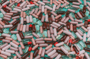 yeşil arka planda çok renkli haplar ve kapsüller