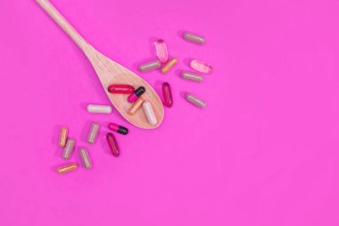 Pembe arka planda çok renkli haplar ve kapsüller.