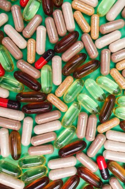 yeşil arka planda çok renkli haplar ve kapsüller