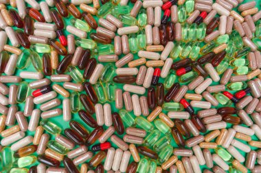 yeşil arka planda çok renkli haplar ve kapsüller
