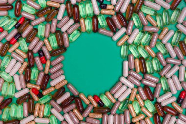 yeşil arka planda çok renkli haplar ve kapsüller