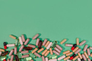 yeşil arka planda çok renkli haplar ve kapsüller