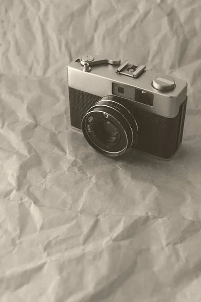 Vintage film camera on crumpled paper background