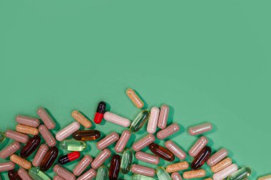 yeşil arka planda çok renkli haplar ve kapsüller