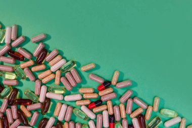 yeşil arka planda çok renkli haplar ve kapsüller