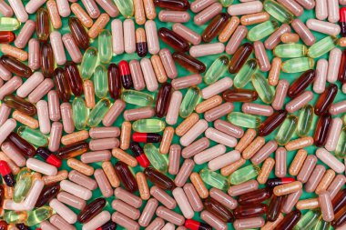 yeşil arka planda çok renkli haplar ve kapsüller