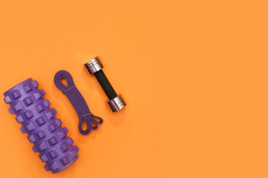 Masaj merdiveni spor emniyet kemeri turuncu arka planda elma ve havlu.