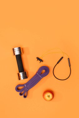 Masaj merdiveni spor emniyet kemeri turuncu arka planda elma ve havlu.