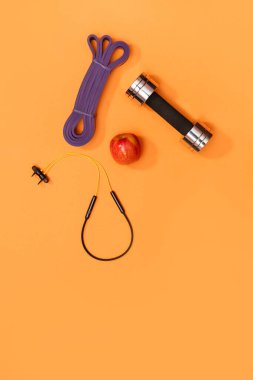 Masaj merdiveni spor emniyet kemeri turuncu arka planda elma ve havlu.