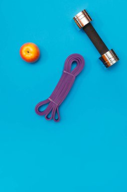 Masaj merdiveni spor tasması mavi arka planda elma ve havlu.