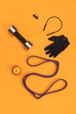 Sarı arka planda masaj merdiveni spor emniyet kemeri elma ve havlu.