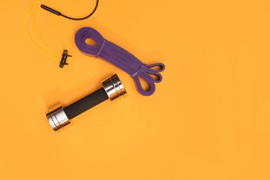 Sarı arka planda masaj merdiveni spor emniyet kemeri elma ve havlu.