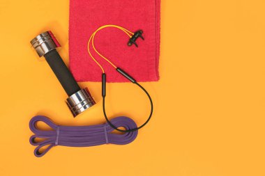 Sarı arka planda masaj merdiveni spor emniyet kemeri elma ve havlu.