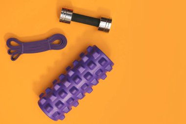 Sarı arka planda masaj merdiveni spor emniyet kemeri elma ve havlu.