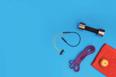 Masaj merdiveni spor tasması mavi arka planda elma ve havlu.