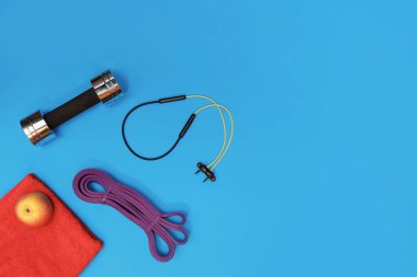 Masaj merdiveni spor tasması mavi arka planda elma ve havlu.