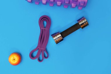 Masaj merdiveni spor tasması mavi arka planda elma ve havlu.