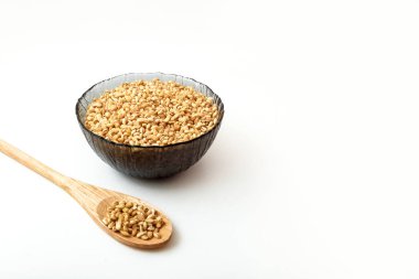 Tahta kaşıkta ve tabakta çiğ inci arpası.