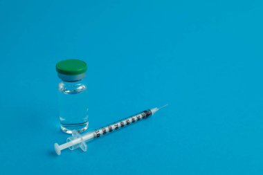 Mavi zemin üzerinde ilaç bulunan şırınga ampulü