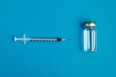 Mavi zemin üzerinde ilaç bulunan şırınga ampulü