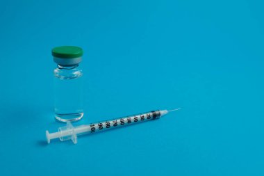 Mavi zemin üzerinde ilaç bulunan şırınga ampulü