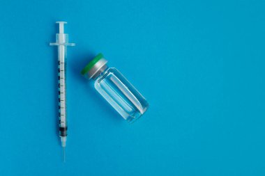 Mavi zemin üzerinde ilaç bulunan şırınga ampulü