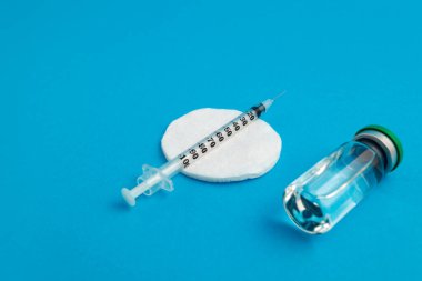 Mavi zemin üzerinde ilaç bulunan şırınga ampulü
