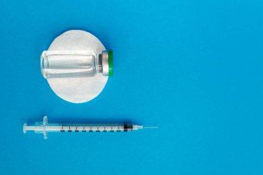 Mavi zemin üzerinde ilaç bulunan şırınga ampulü