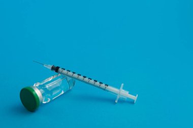 Mavi zemin üzerinde ilaç bulunan şırınga ampulü