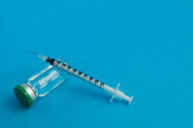 Mavi zemin üzerinde ilaç bulunan şırınga ampulü