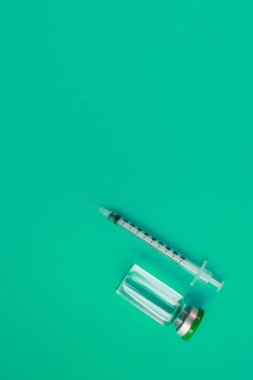 Yeşil zemin üzerinde ilaç bulunan şırınga ampulü